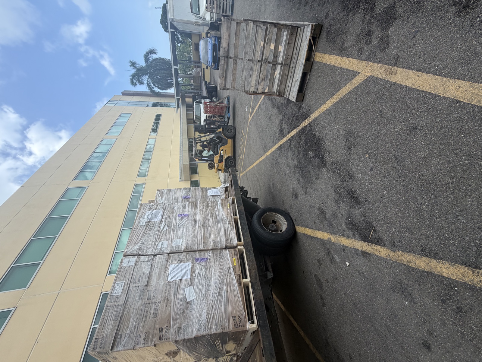 Palletized supplies on a delivery truck beside a forklift